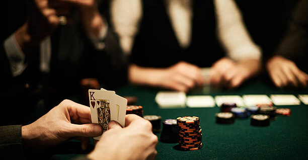 Hands of card player holding king of hearts