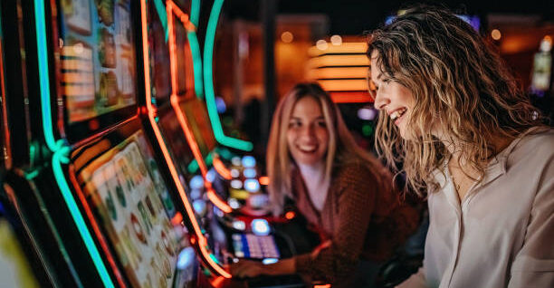Girl friends gambling in casino on slot machinery