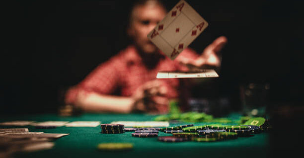 One mature man playing poker late by night, throwing playing cards on table.
