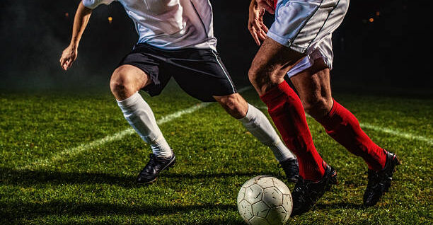 Two soccer players challenging for the ball, low angle view.